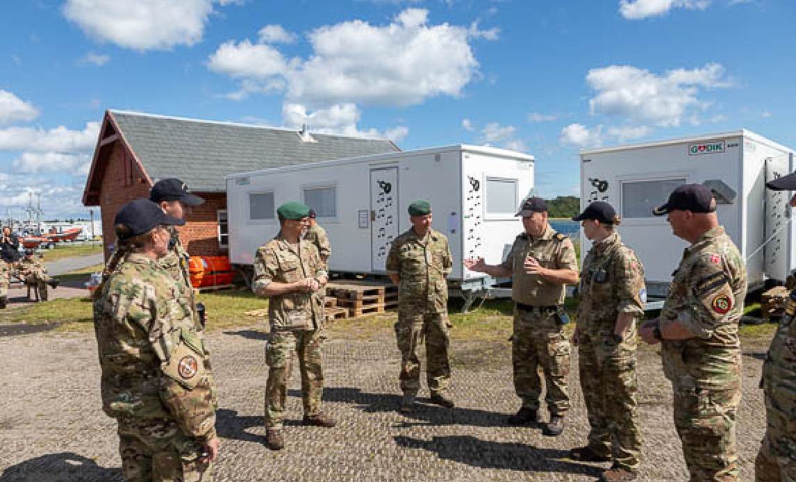 Gruppe af Hjemmeværnssoldater står i ring til briefing under Uddannelsesugen i Marinehjemmeværnet.