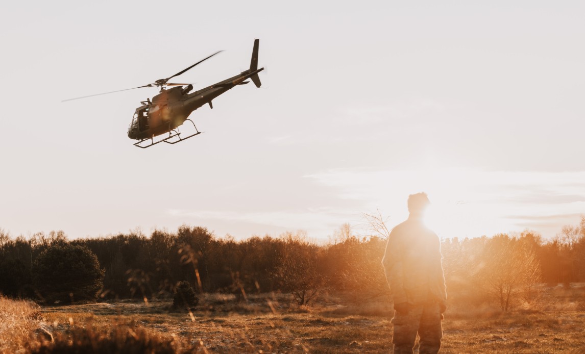 En helikopter flyver væk i en solnedgang