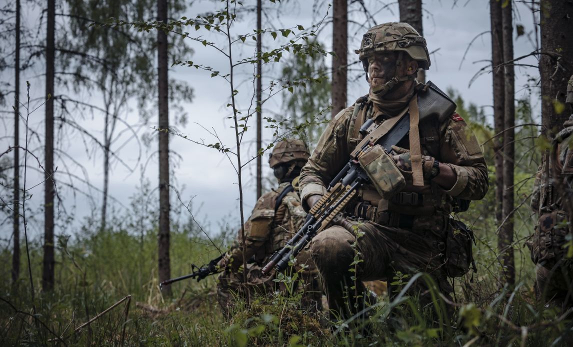 Soldat sidder klar i en skov.