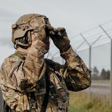 Soldat på flyvestation kigger gennem kikkert.