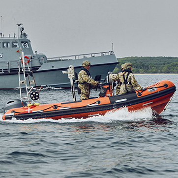 Gummibåd sejler langs et af Marinehjemmeværnets grå fartøjer